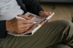 elderly man solving a crossword puzzle
